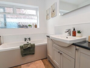 Ein modernes Badezimmer mit Badewanne, Waschbecken und Fenster.