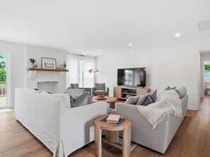 Ein modernes Wohnzimmer mit einem weißen Sofa, einem grauen Sofa, einem Couchtisch und einem Fernseher.