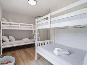 Une chambre avec un lit superposé, une armoire et un petit bac de rangement.
