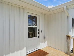 A white door with a glass panel, a small porch with a wooden railing, and a brown doormat. - Sunny Days - Access The Masonboro Sound (Wilmington)
