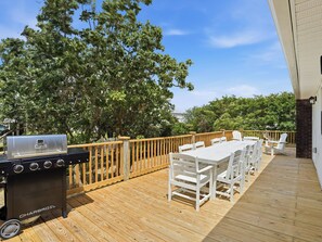 Eine Terrasse im Freien mit Grill, Esstisch und Holzgeländer.
