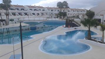 Ein Schwimmbadbereich mit mehreren Pools und einem Rettungsschwimmerstand.