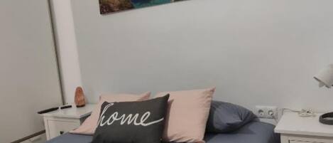 Un dormitorio con cama, mesita de noche y un cuadro colgado en la pared.
