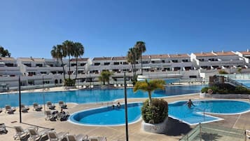 A resort with multiple swimming pools, lounge chairs, and palm trees.