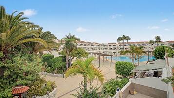 Ein Resort mit Swimmingpool, Palmen und einem gefliesten Weg.