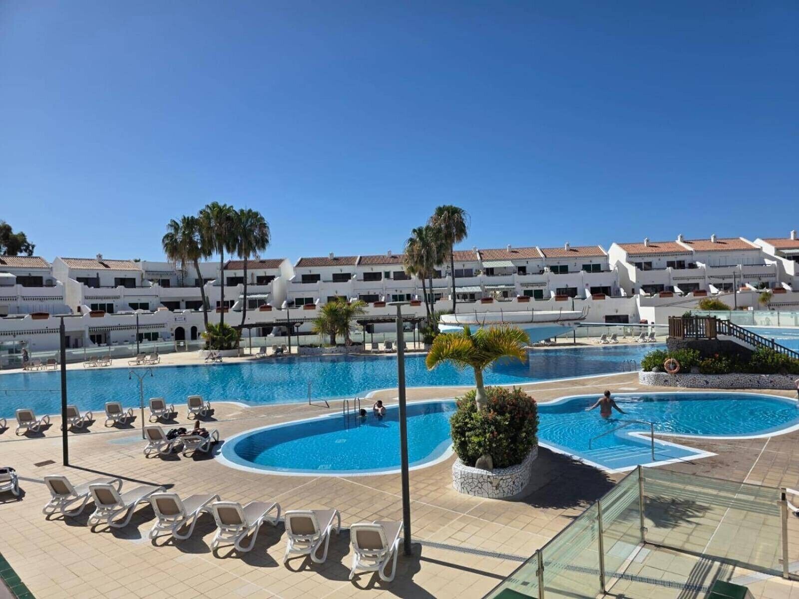 Un complexe hôtelier doté de plusieurs piscines, de chaises longues et de palmiers.