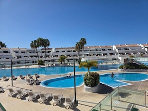 Ein Resort mit mehreren Swimmingpools, Liegestühlen und Palmen.