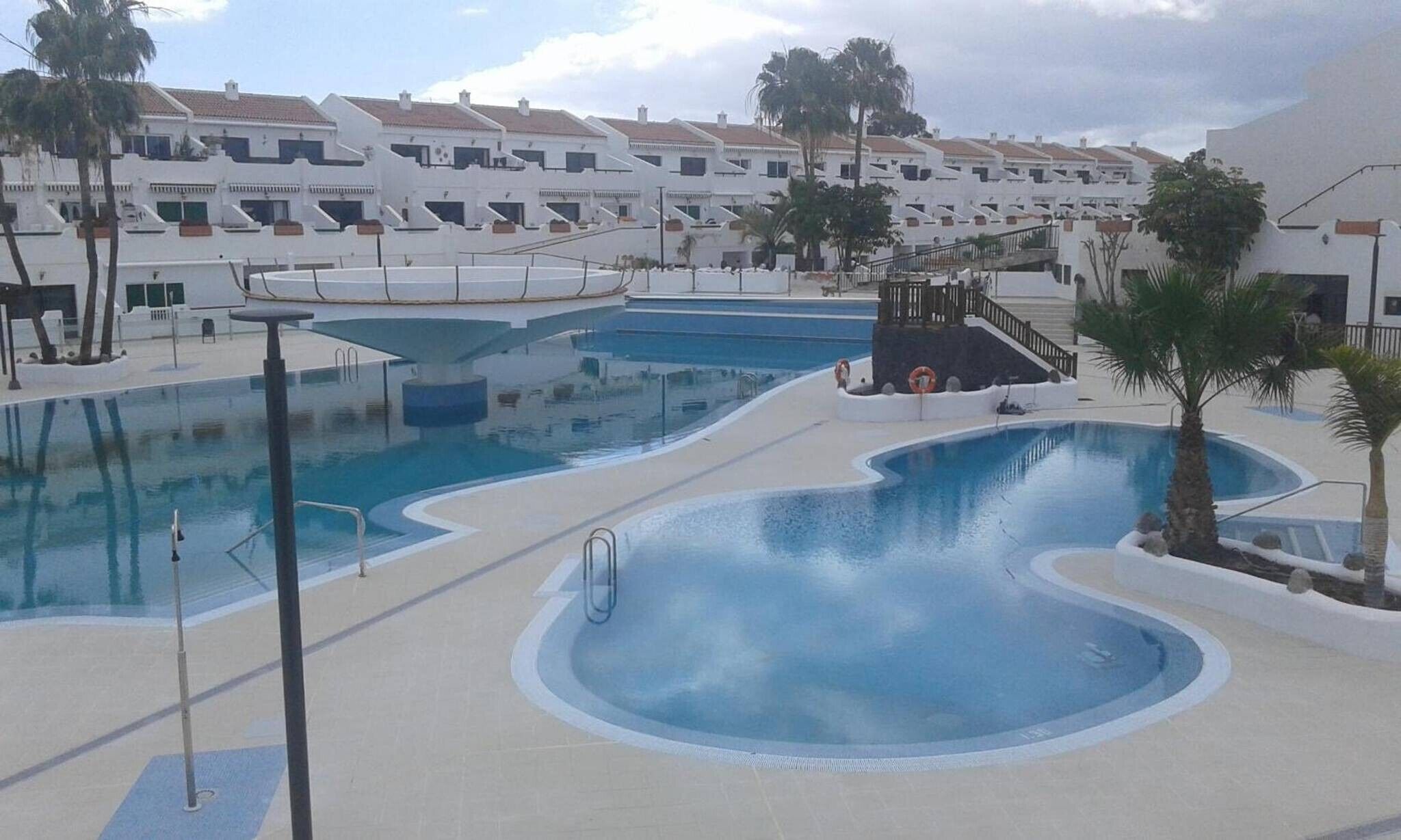 Un área de piscina con varias piscinas y un puesto de socorristas.