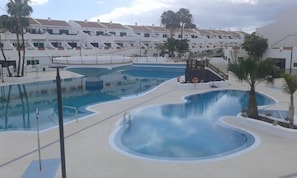 A swimming pool area with multiple pools and a lifeguard stand. - Vacation Apartment '3 Habitaciones' with Shared Pool, Shared Terrace and Wi-Fi (Costa del Silencio)