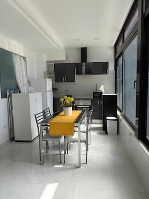A modern kitchen with a dining area, white cabinetry, a built-in oven, and a window with a view. - Vacation Apartment '3 Habitaciones' with Shared Pool, Shared Terrace and Wi-Fi (Costa del Silencio)