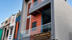 Um hotel moderno com uma placa de destaque para Hotel Kridhi Ka Inn, apresentando uma estrutura de dois andares com varandas e uma combinação de elementos de fachada em vidro e paredes sólidas.