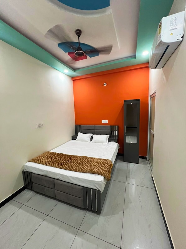 Un dormitorio con cama, ventilador de techo, aire acondicionado y una puerta que da a otra habitación.