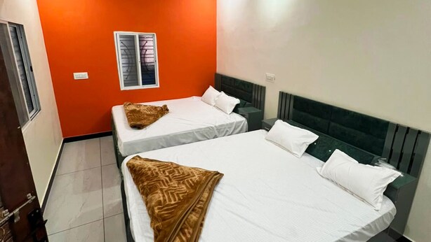 Quarto de hotel com duas camas, um ventilador de teto, uma janela com grades e piso de azulejos.