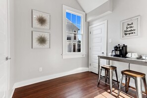 A kitchen with a window, a coffee maker, and two stools. - Cozy Historic Home 5 Bedrooms Centrally Located (New Orleans)
