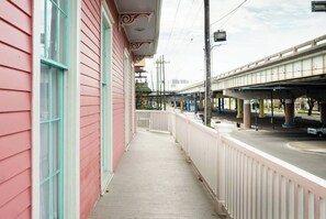 A covered outdoor area with a white railing, a pink building, and a bridge overhead. - LaBranche Pharmacy | Step Back in Time in a Historic Tremé Landmark- Walk to French Quarter (New Orleans)