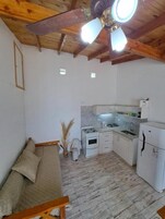 Habitación pequeña con cama, kitchenette y ventilador de techo.