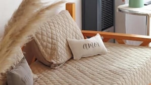 Un lit avec une couverture matelassée, un oreiller orné du mot « amor » et un cadre en bois.