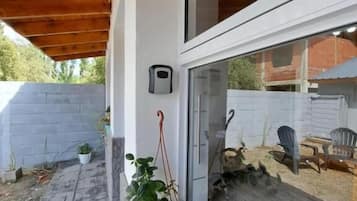 Un espace extérieur abrité, doté d’un plafond en bois, d’une plante en pot, d’une fenêtre et d’une chaise.