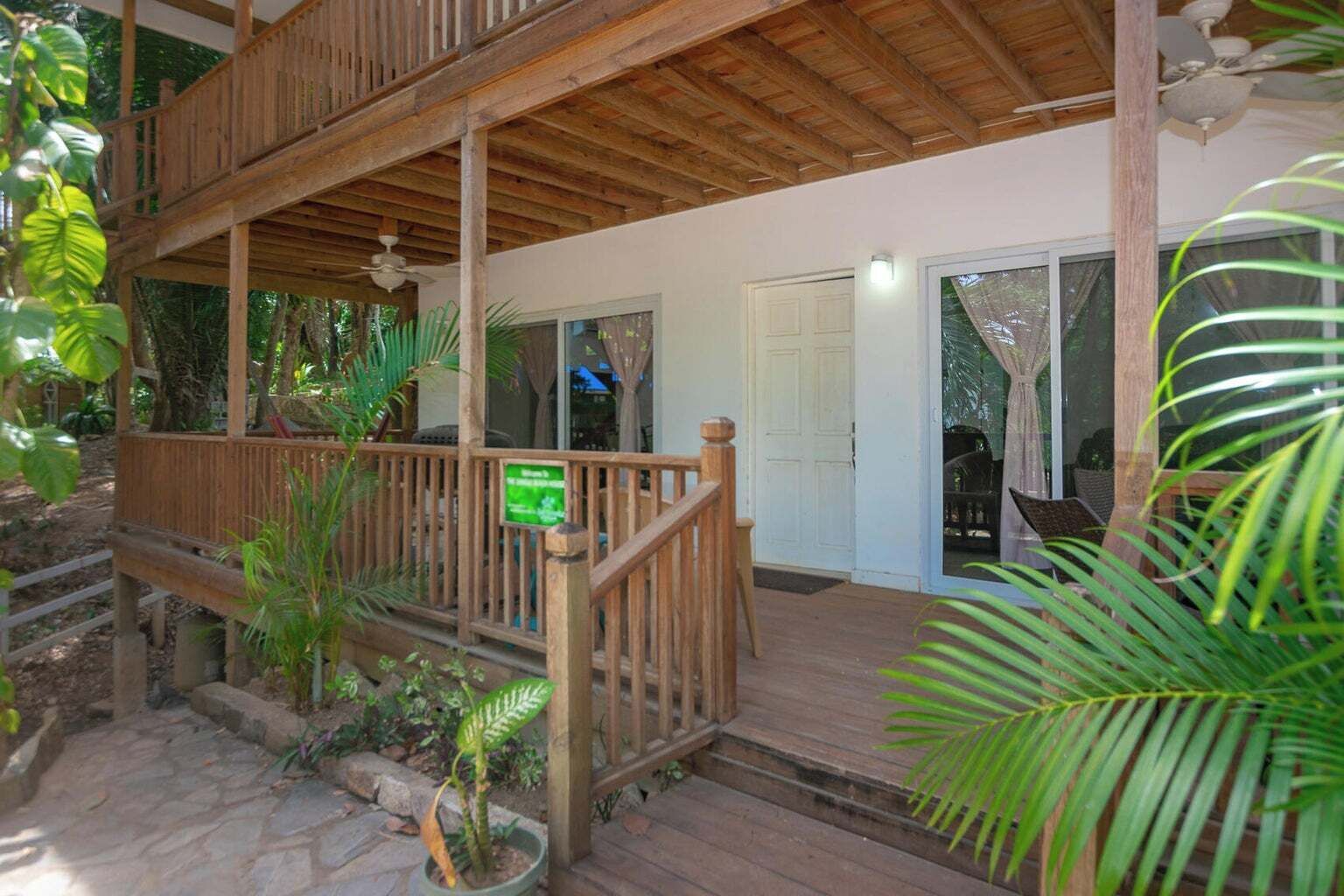 A wooden deck with a railing, a door, and potted plants.