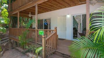 A wooden deck with a railing, a door, and potted plants.