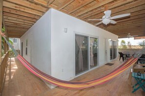 Ein Zimmer mit einer Hängematte, einem Deckenventilator und einer Terrasse mit Gartenmöbeln.