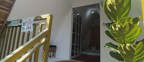 Una escalera con un cartel de 'No Smoking', un tapete tejido en la parte inferior y una planta en maceta.