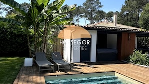 Un área de piscina con sillas de descanso y una terraza de madera.