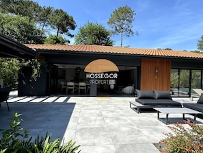 Una casa moderna con un patio, mobiliario exterior y un juego de comedor.