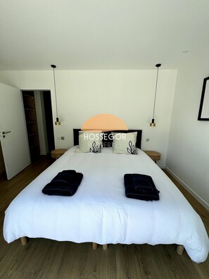 A bedroom with a large bed, two bedside tables, a wardrobe, and a door leading to another room. - Villa Murmur - Seignosse - Pool - Jacuzzi (Seignosse)