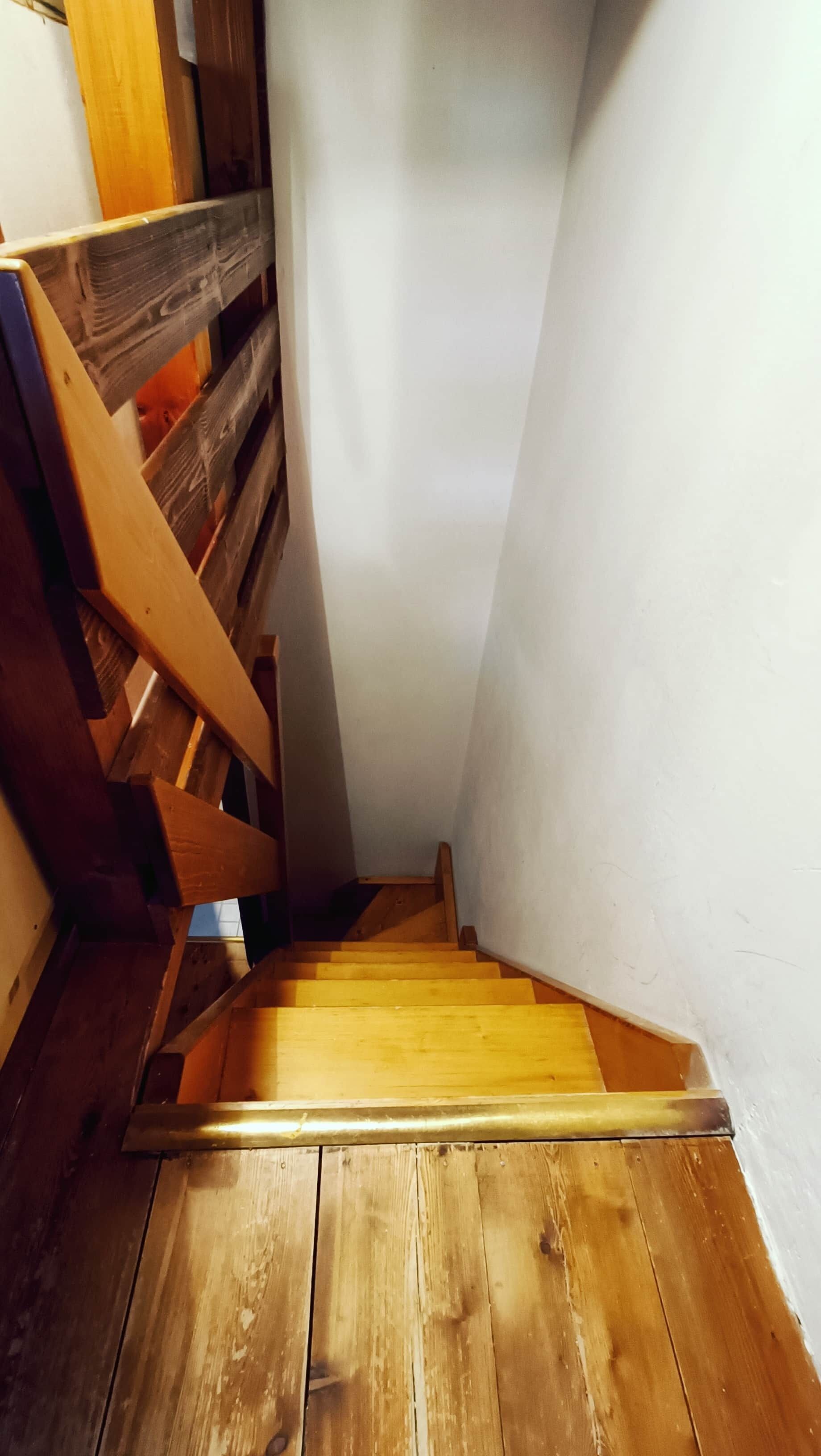 Eine Holztreppe mit Geländer, das zu einer Zwischenebene führt.