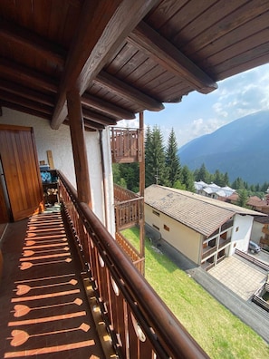 A wooden balcony with a view of a mountain and a residential area. - Appartamento Monti e sole (Folgarida)