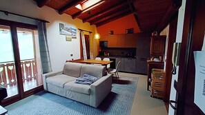 Un salon confortable avec un canapé, une table à manger et une cuisine en arrière-plan.