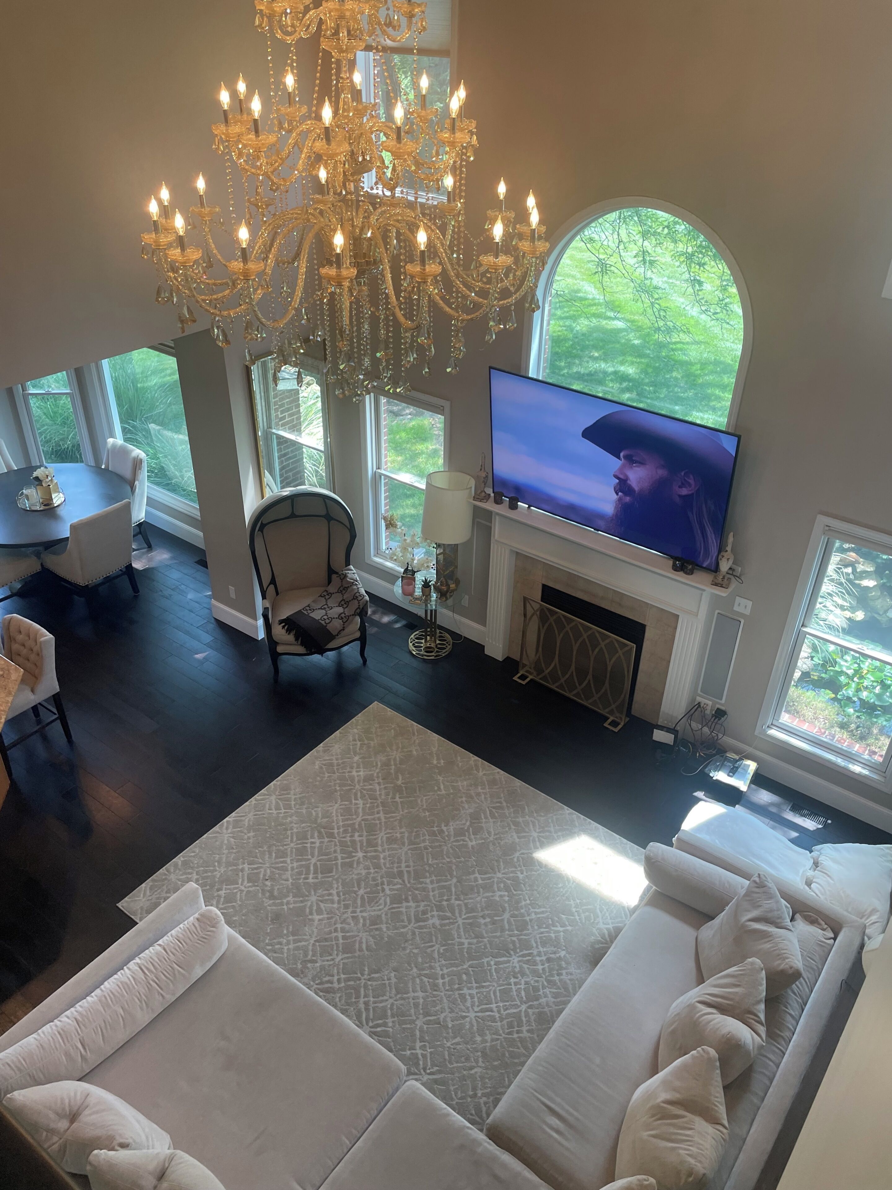 A spacious living room with a large chandelier, a television, and a fireplace.