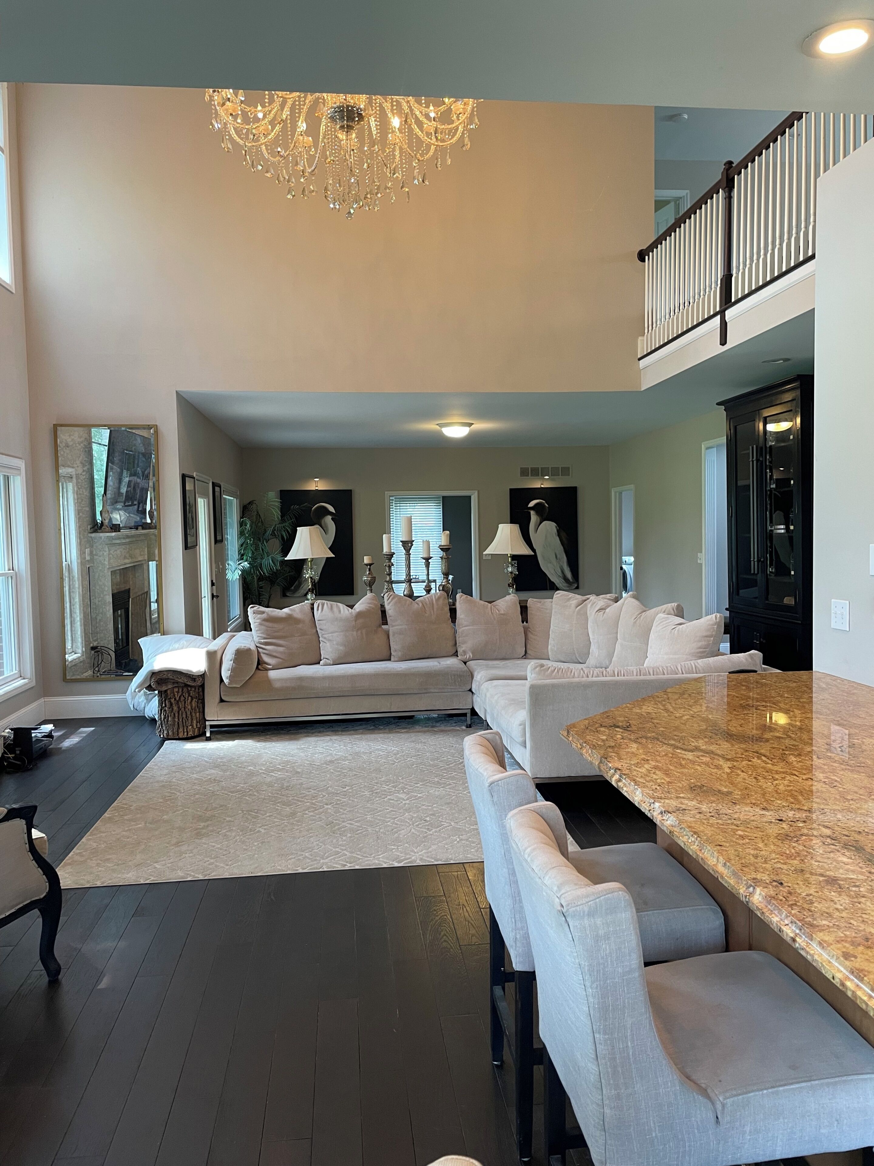 A spacious living room with a large sectional sofa, a dining area with a granite countertop, and a chandelier.