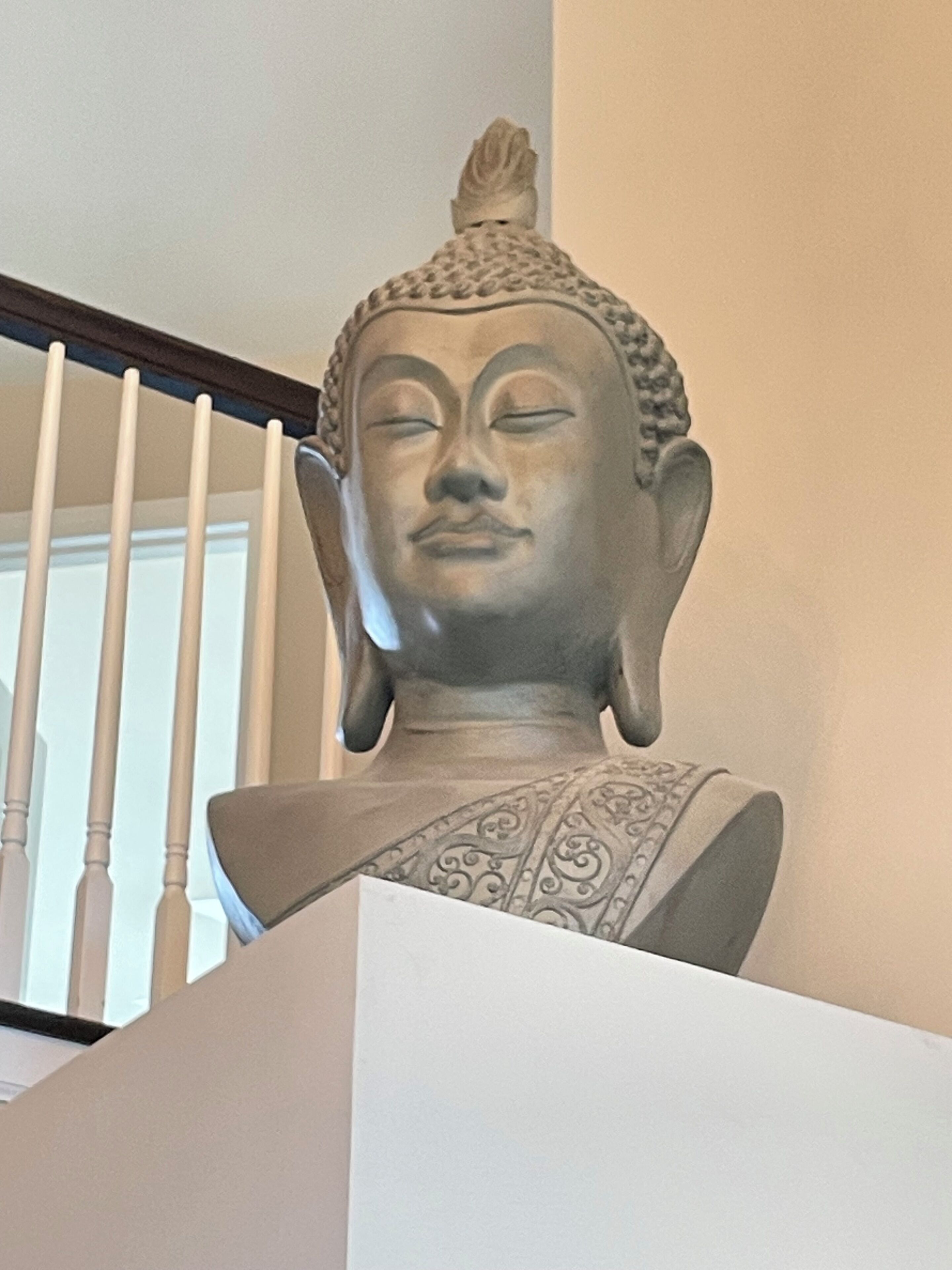 A statue of a seated figure with a rounded head and a decorative headdress.