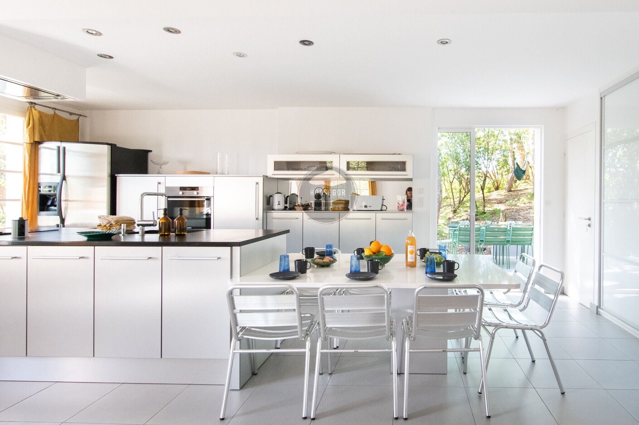 A modern kitchen with white cabinets, a dining table with chairs, and a view of the outdoors.