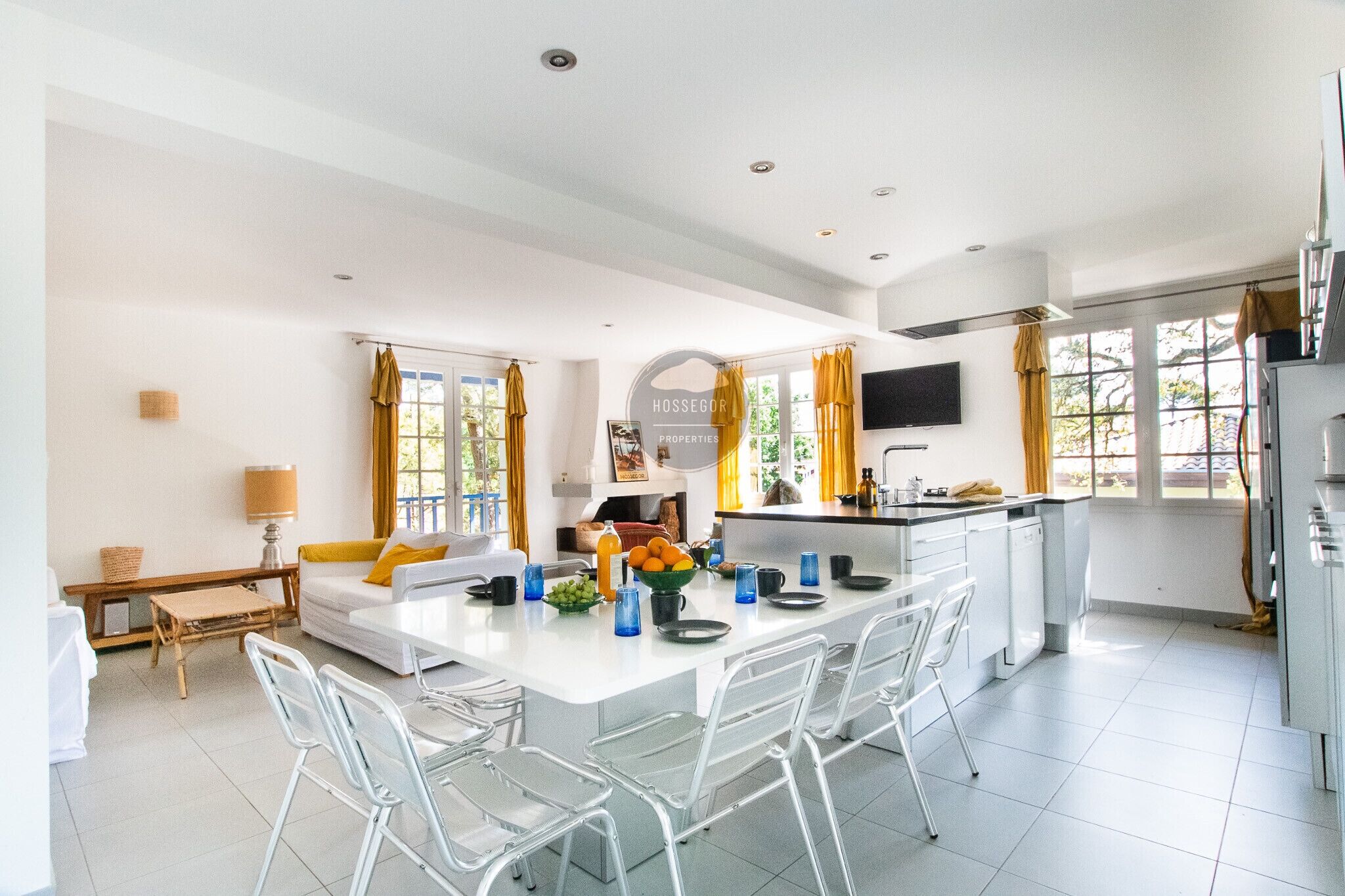 A modern kitchen with a central island, white cabinetry, and a dining area with chairs.