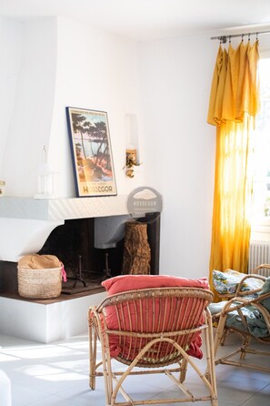 A living room with a fireplace, wicker furniture, and a yellow curtain.
