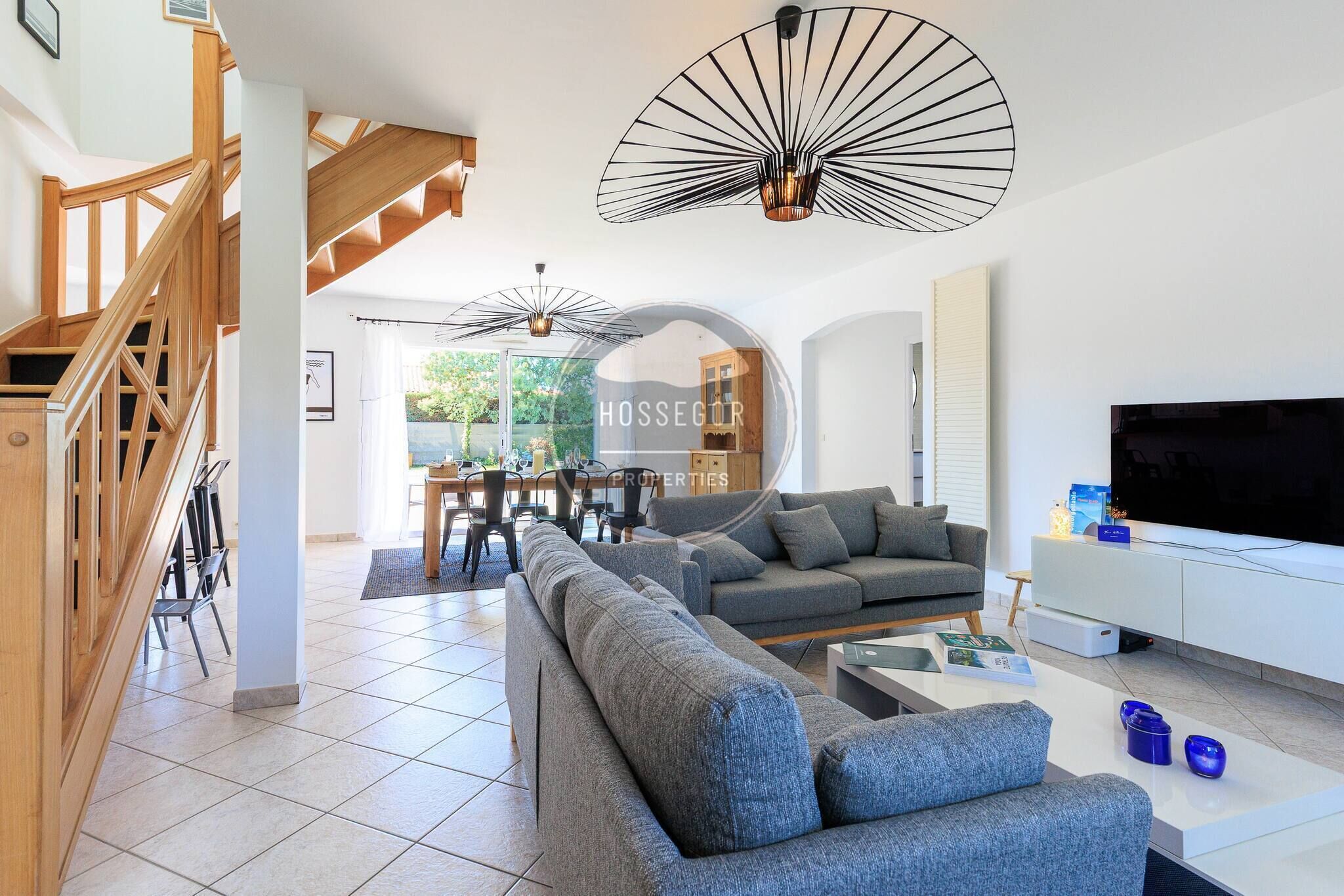 A modern living room with a sofa, a TV, and a dining area with chairs and a table.