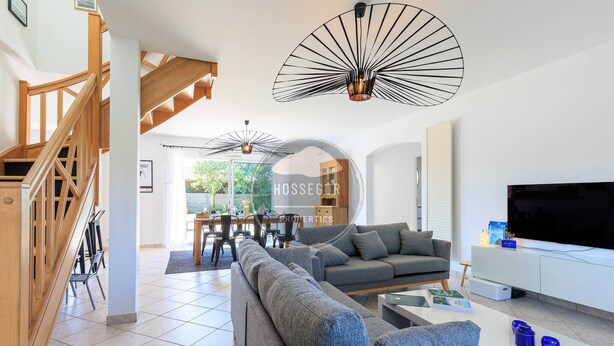 Ein modernes Wohnzimmer mit Sofa, Fernseher und Essbereich mit Stühlen und Tisch.