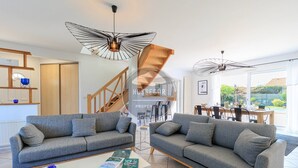 Ein modernes Wohnzimmer mit zwei grauen Sofas, einem weißen Couchtisch und einem Essbereich mit einem Holztisch und Stühlen.