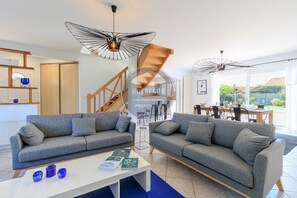 Ein modernes Wohnzimmer mit zwei grauen Sofas, einem weißen Couchtisch und einem Essbereich mit einem Holztisch und Stühlen.