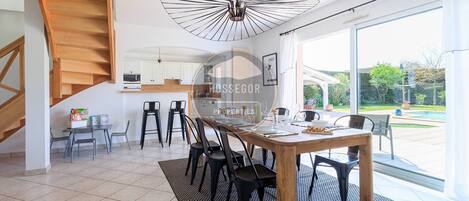 Un comedor amplio con una mesa de madera, sillas negras y un gran ventanal con vistas al exterior.