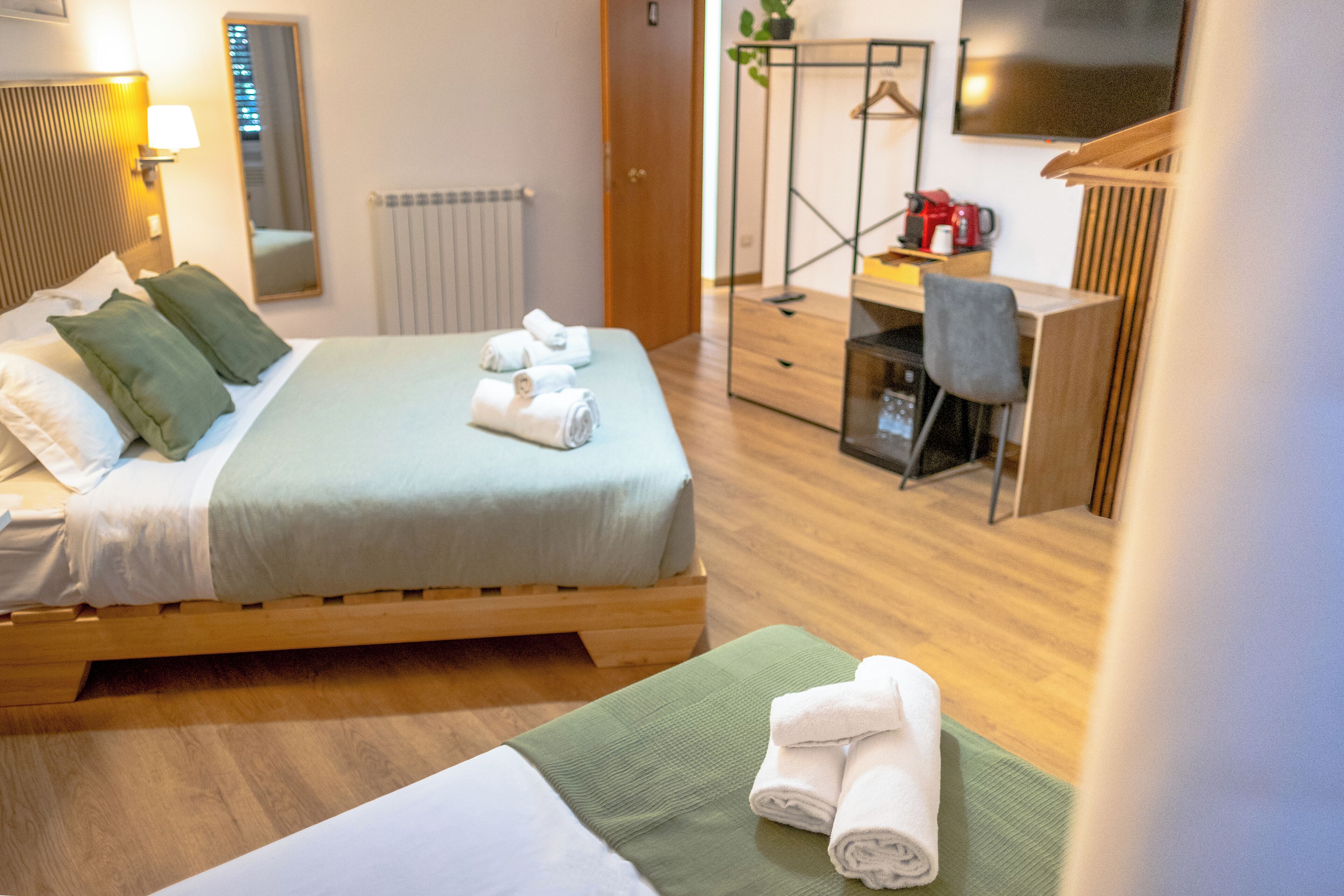 A hotel room with a bed, a desk, a chair, and a TV.