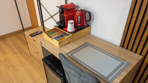 A compact kitchenette with a coffee maker, a remote control, and a drawer with snacks.