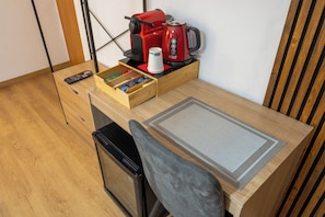 A compact kitchenette with a coffee maker, a remote control, and a drawer with snacks.