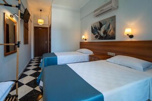 Hotelkamer met twee bedden, een geruite vloer, een schilderij aan de muur en een luchtverfrisser aan de wand.