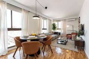 A modern living room with a dining area, large windows, and a view of the city. - Apartamento de 2 habitaciones totalmente reformado y equipado, situado en Calle Juan Álvarez Mendizábal, a un paso de la Plaza de España, el Templo de Debod y Gran Vía (MADRID)