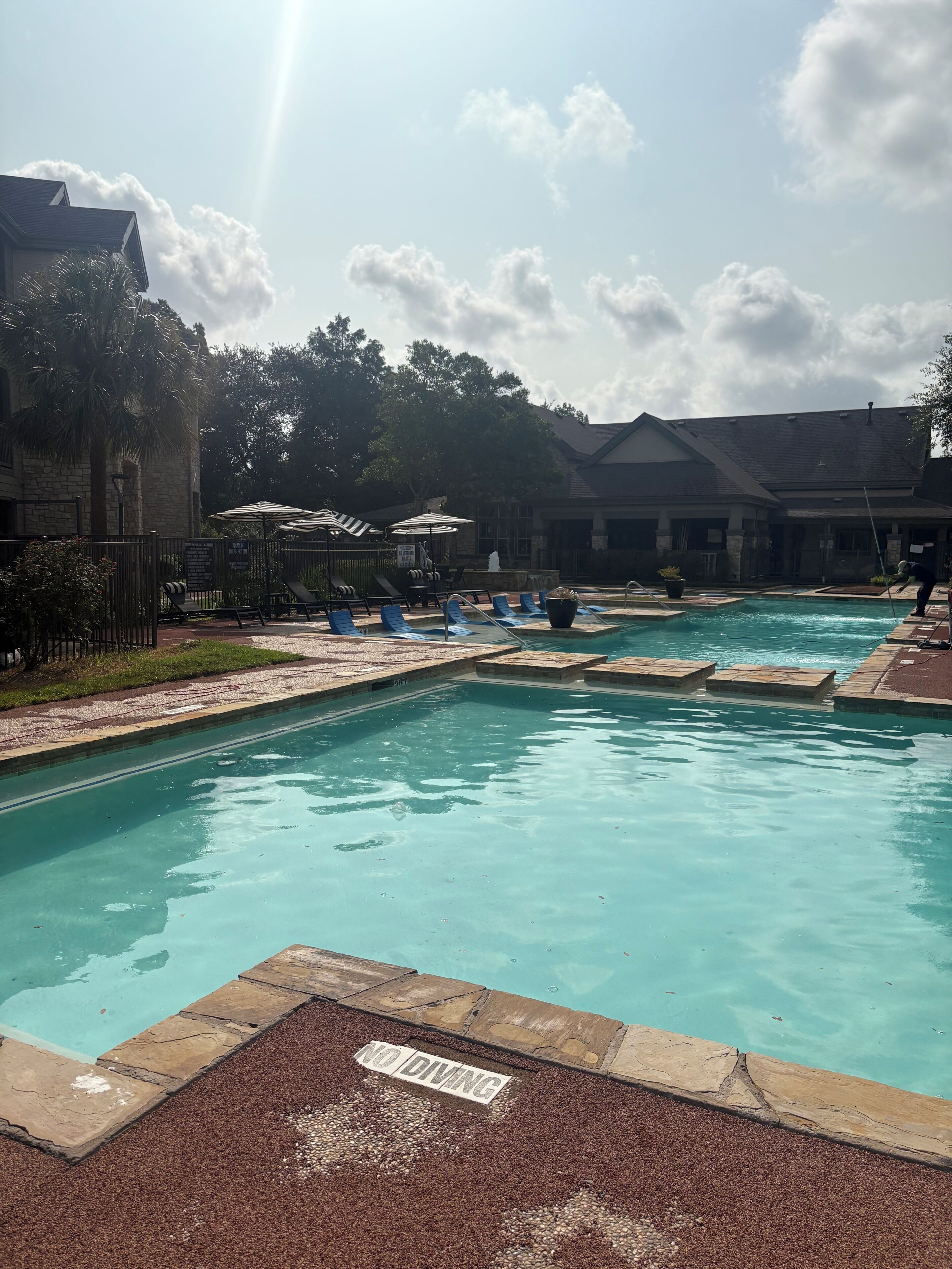 A swimming pool with lounge chairs and a 'NO DIVING' sign.
