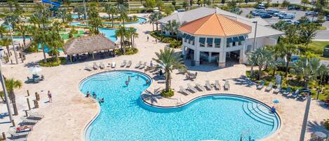 Ein Resort mit einem großen, gewundenen Swimmingpool, umgeben von Liegestühlen und Palmen.